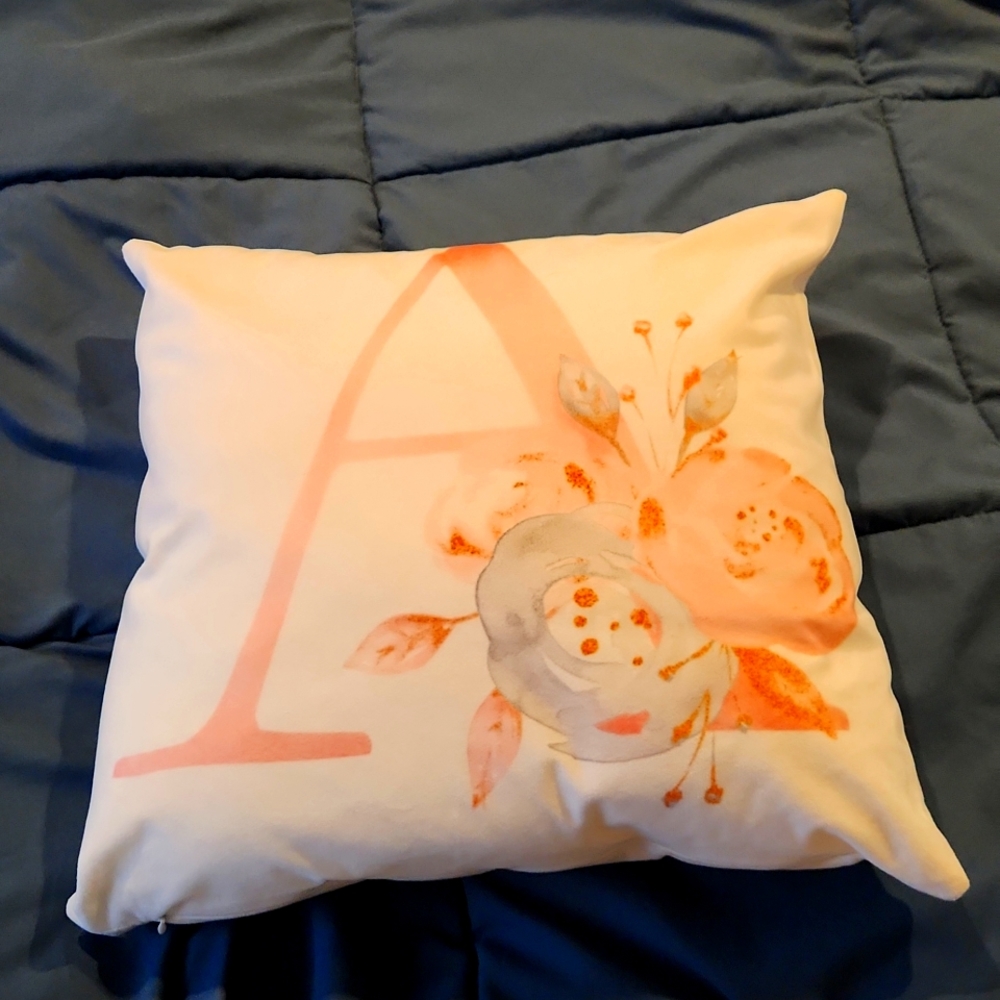 Monogrammed decorative pillow with an A in it with flowers around it.
